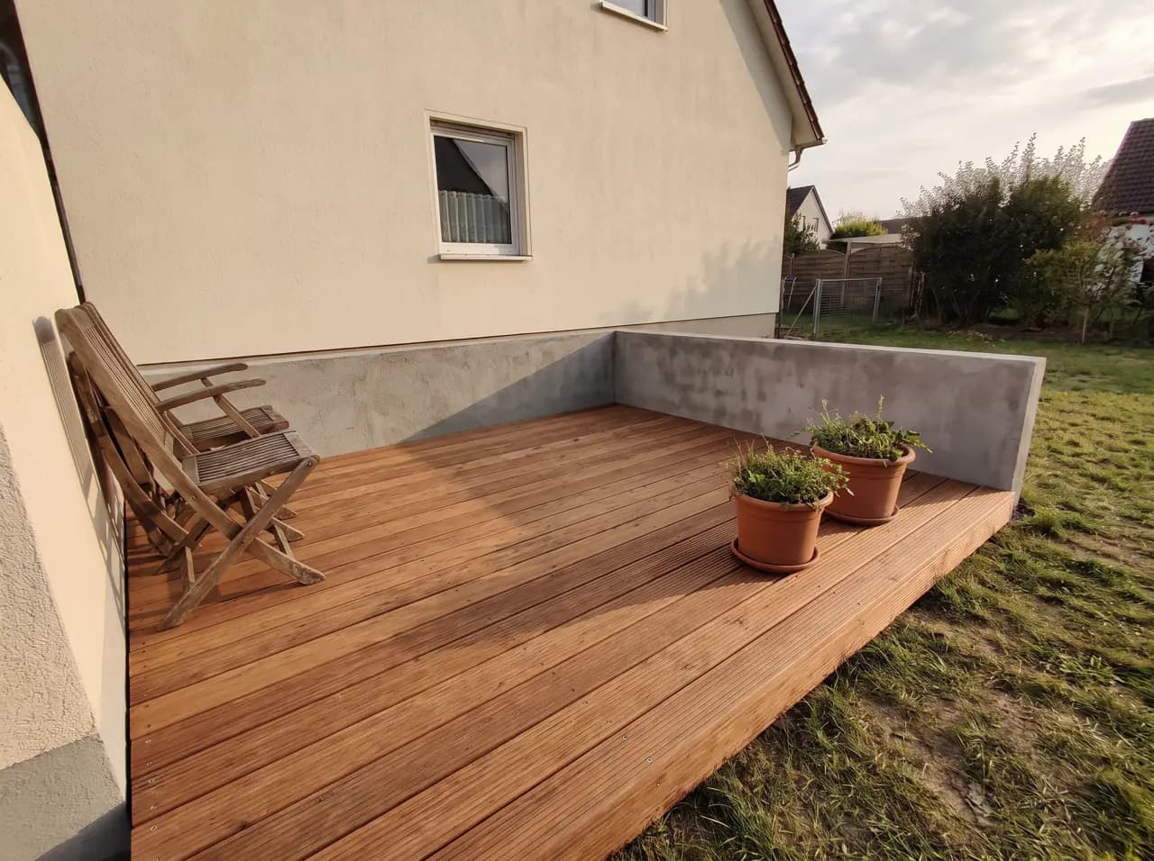 Titelbild des Bereichs Terrasse: fertig verlegte Holzterrasse mit Pflanzkübeln.